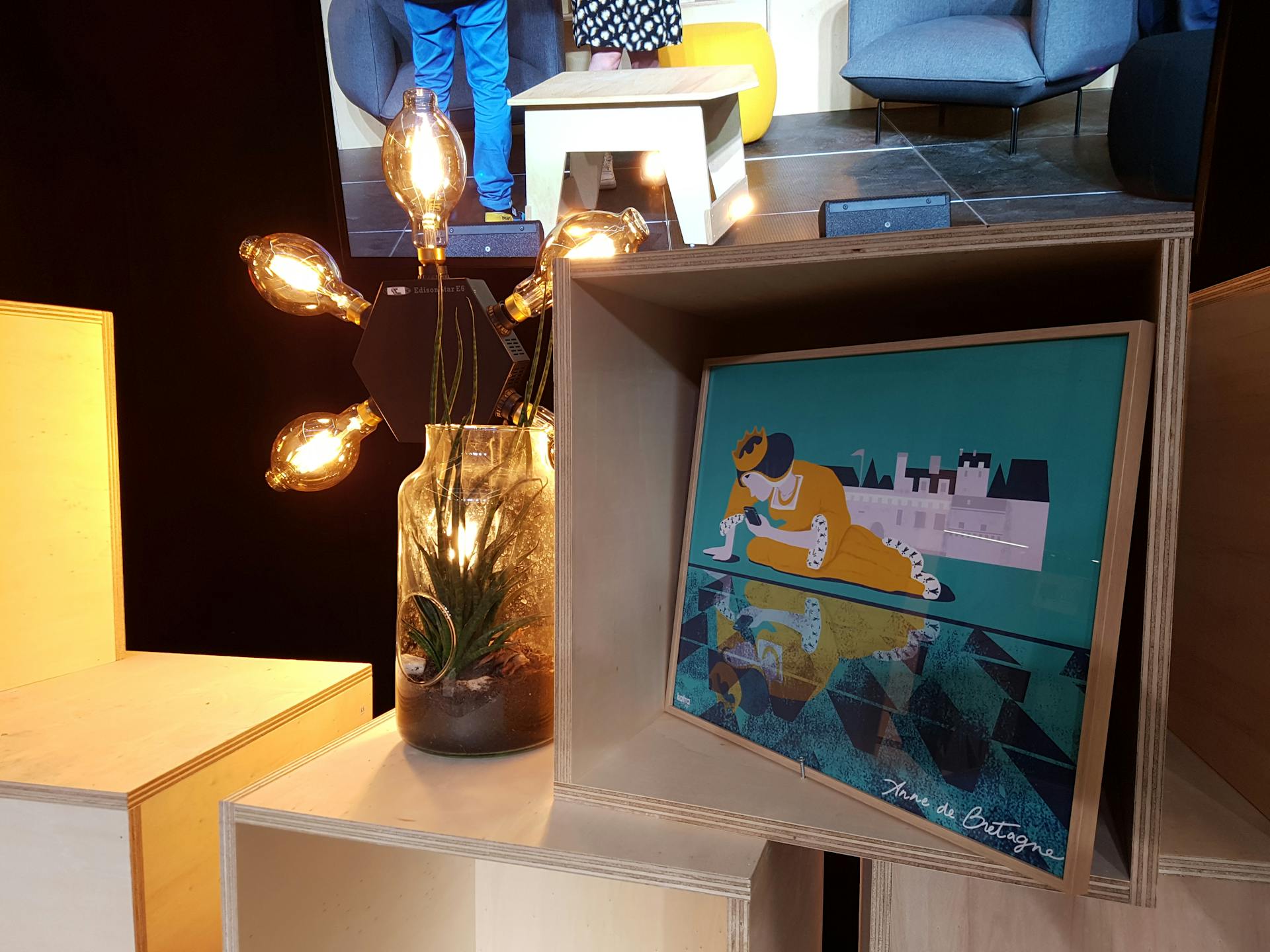 Zoom sur certains des détails de la scénographie de la Nantes Digital Week. La photo représente des cubes en bois empilés, supportant une lampe et une peinture du Studio Katra.