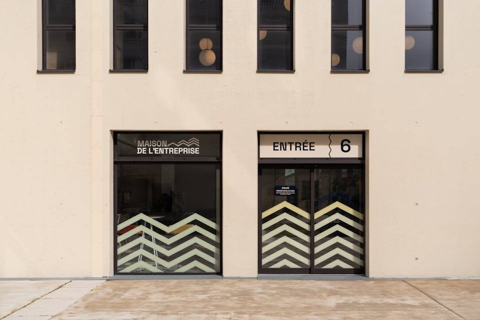 L'extérieur des nouveaux locaux de la maison de l'entreprise à Saint-Nazaire, aménagés par l'agence de design d'espace Studio Katra. On y voit des portes automatiques avec des vitrophanies en formes de vagues.
