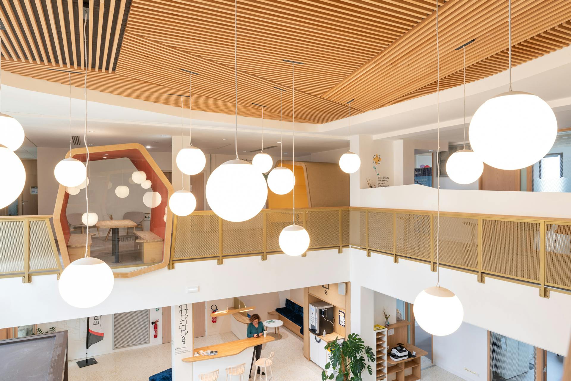 Le premier étage de la nouvelle Maison de l'Entreprise à Saint-Nazaire, dont l'aménagement d'intérieur a été réalisé par Studio Katra. On y voit une cabine d'isolation dédiée aux réunions, ainsi que de nombreux luminaires.