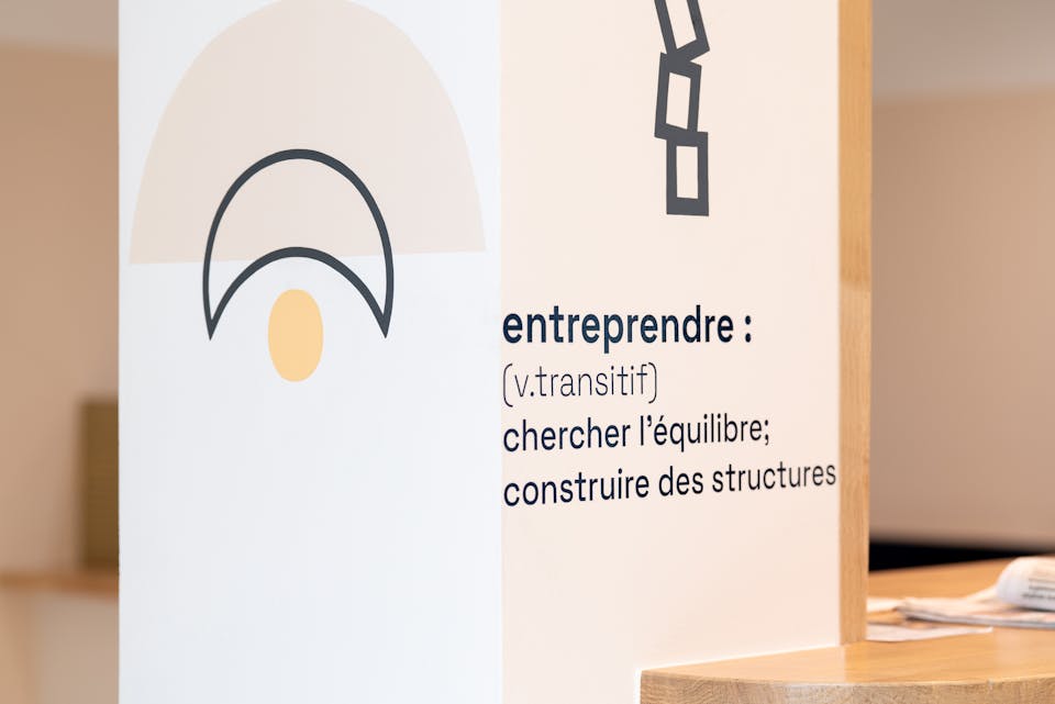 Une illustration filaire symbolisant des tasses empilées les unes sur les autres, apposée par sticker dans le cadre de l'aménagement de la Maison de l'Entreprise à Saint-Nazaire par l'agence de design Studio Katra. On peut y lire "entreprendre : chercher l'équilibre, construire des structures".