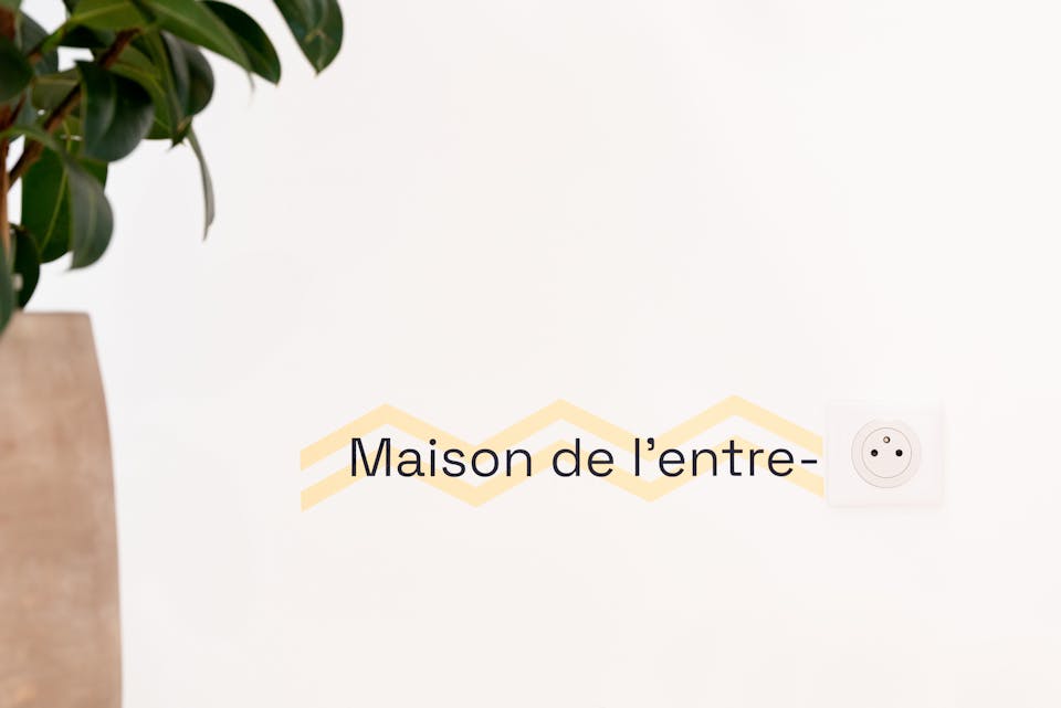 Jeu de mot graphique peint sur un mur. On peut y lire "Maison de l'entreprise", où la sonorité "prise" est symbolisée par une prise électrique fixée au mur.