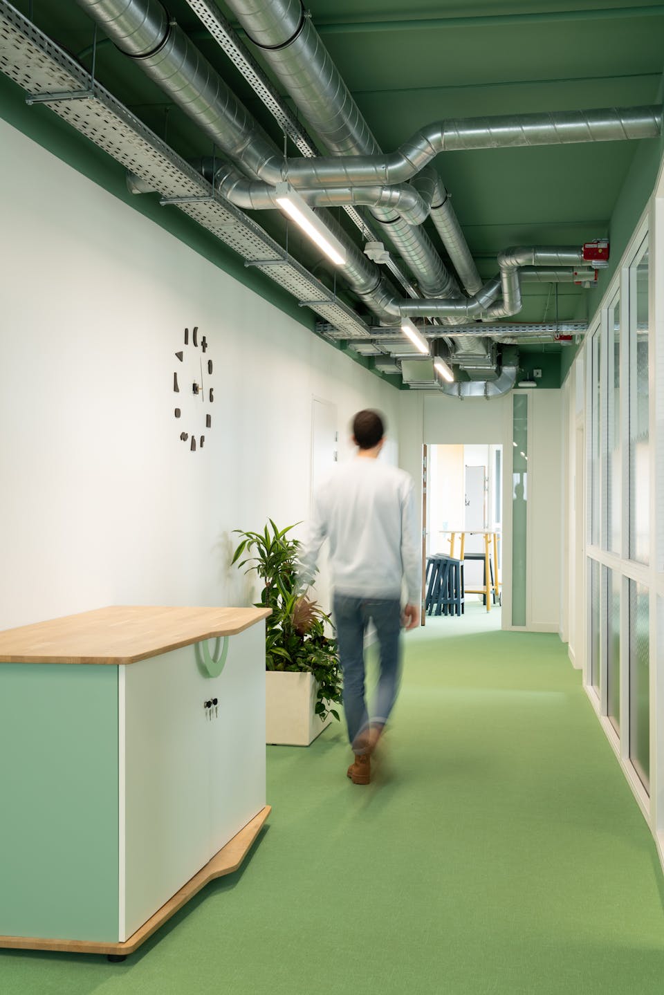 Une personne marchant au milieu d'un couloir peint en vert au cœur de la Maison de l'Entreprise par Peinture Nantaise et l'agence de design Studio Katra.