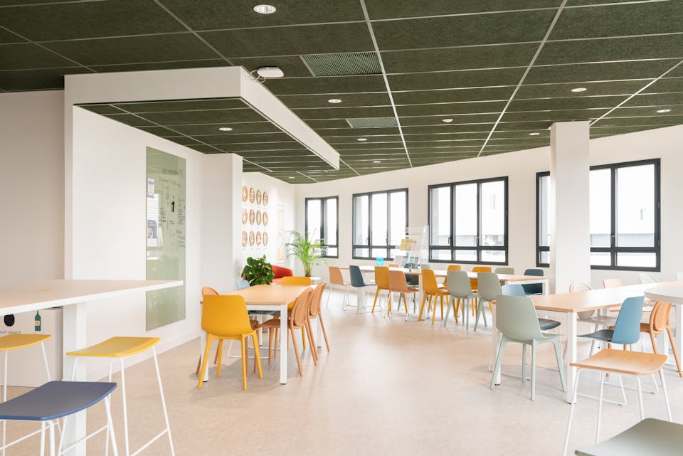 Une grande salle à manger au sein de la Maison de l'Entreprise de Saint-Nazaire, où sont logées de nombreuses tables et chaises.