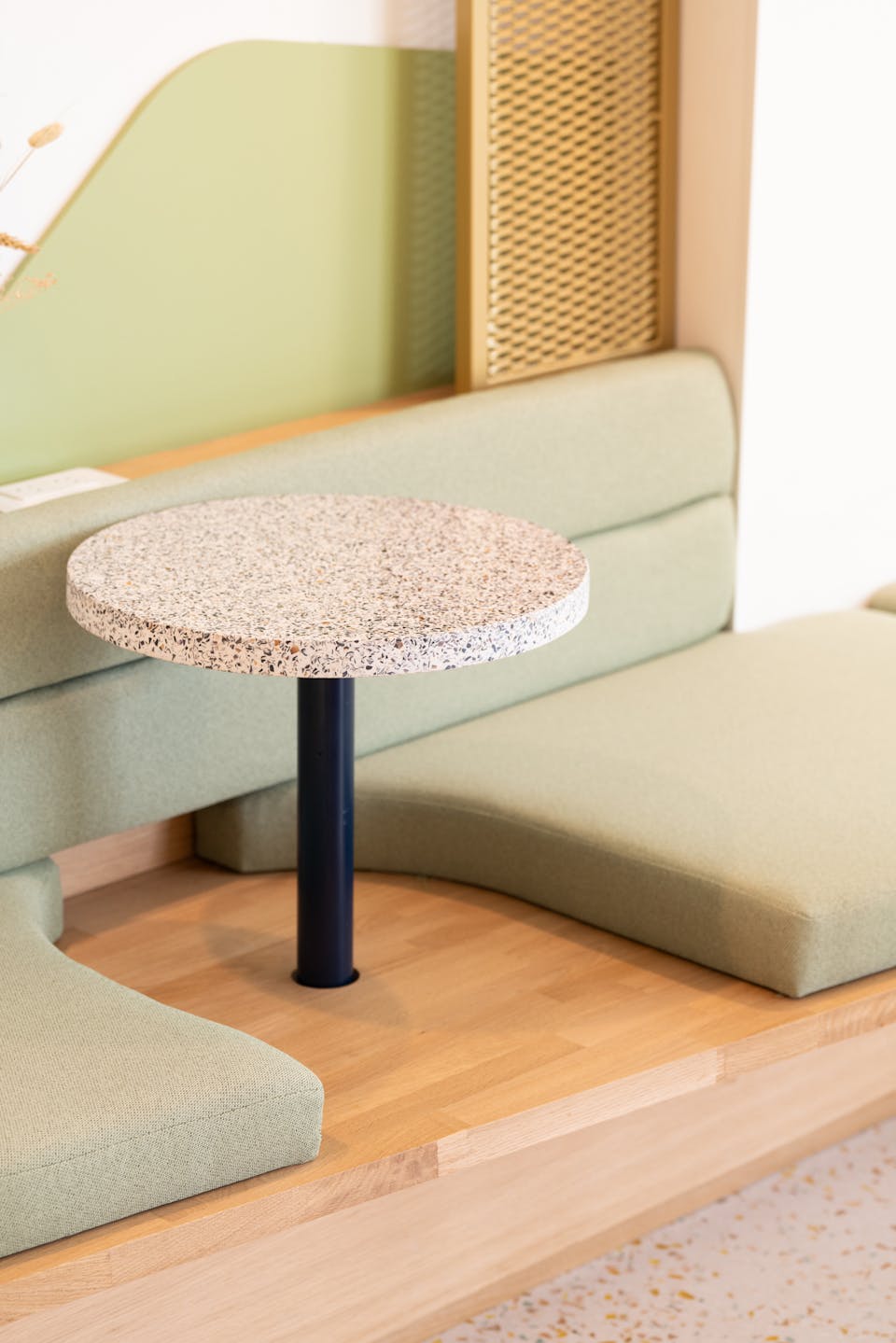 Une petite table ronde incorporée à une assise en bois conçue par l'agence de design Katra et fabriquées par Ici Nantes, servant l'aménagement d'intérieur de la nouvelle Maison de l'Entreprise à Saint-Nazaire. 