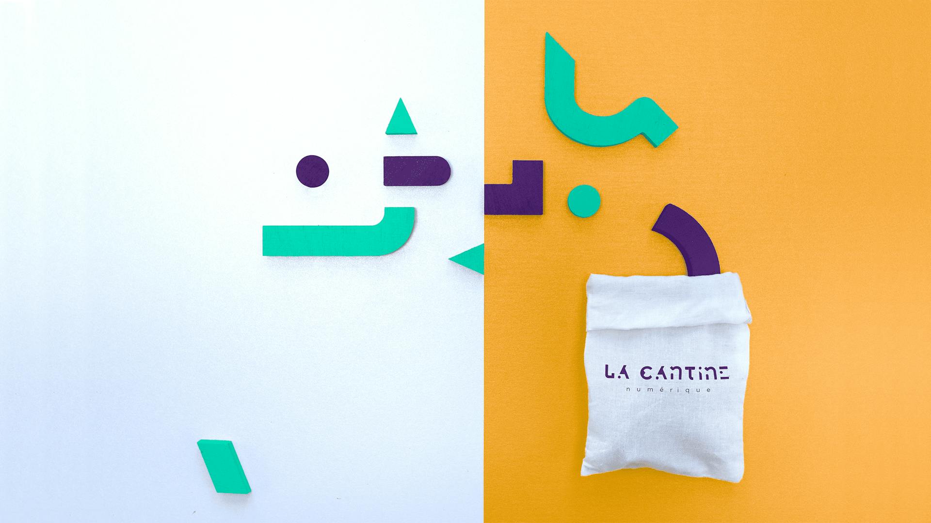 Un sachet étiqueté "Cantine Numérique" dont sortent des formes géométriques de couleurs verte et mauve.