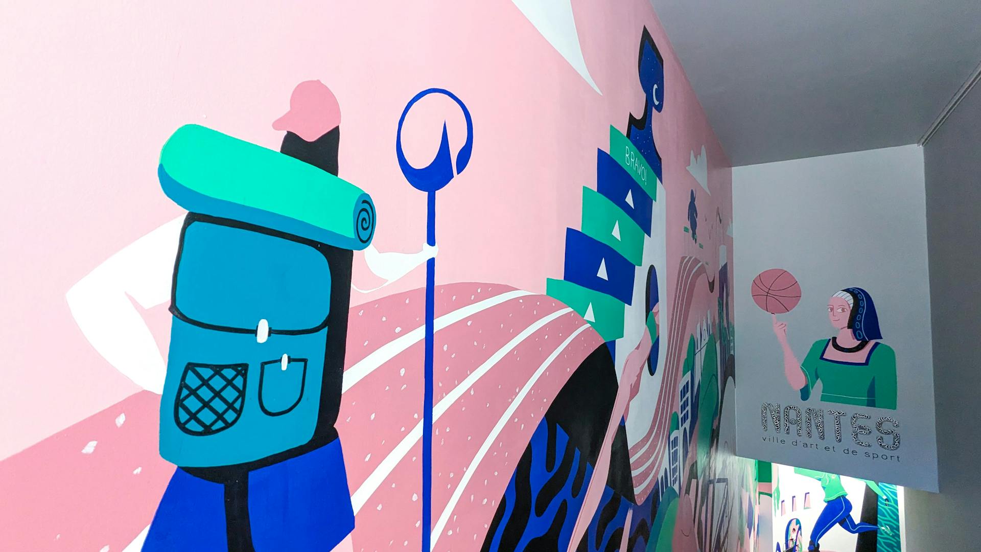 Zoom sur une partie de la fresque de l'agence de design graphique Studio Katra au sein du Décathlon City de Nantes, représentant un voyageur marchant sur une piste d'athlétisme, tenant à la main un bâton au logo de Décathlon.