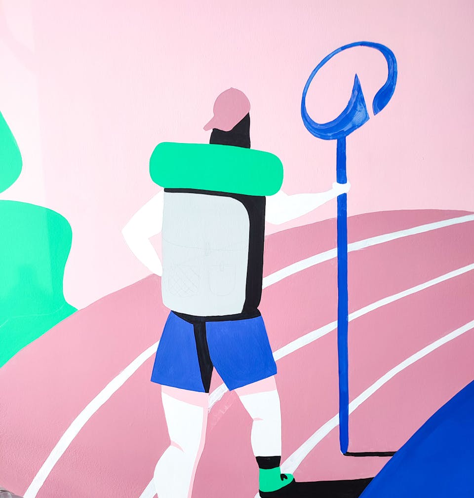 Zoom sur une partie de la fresque de l'agence de design graphique Studio Katra au sein du Décathlon City de Nantes, représentant un voyageur marchant sur une piste d'athlétisme, tenant à la main un bâton au logo de Décathlon.