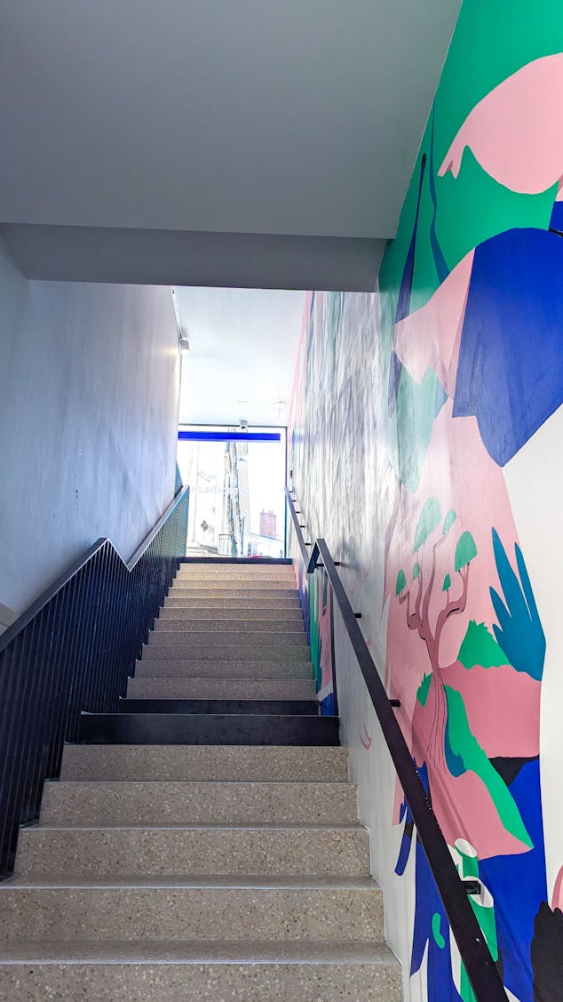 La cage d'escalier du nouveau Décathlon City, accueillant une fresque de l'agence de Design Graphique Studio Katra.