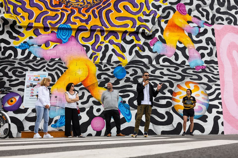 Un espace industriel transformé par une fresque street art de l'artiste Ocü et de l'agence de design Studio Katra, formant un terrain de design actif destiné à la pratique du handball gaélique. On y voit les membres de Nantes Métropole présenter ce nouveau site de Design Actif.