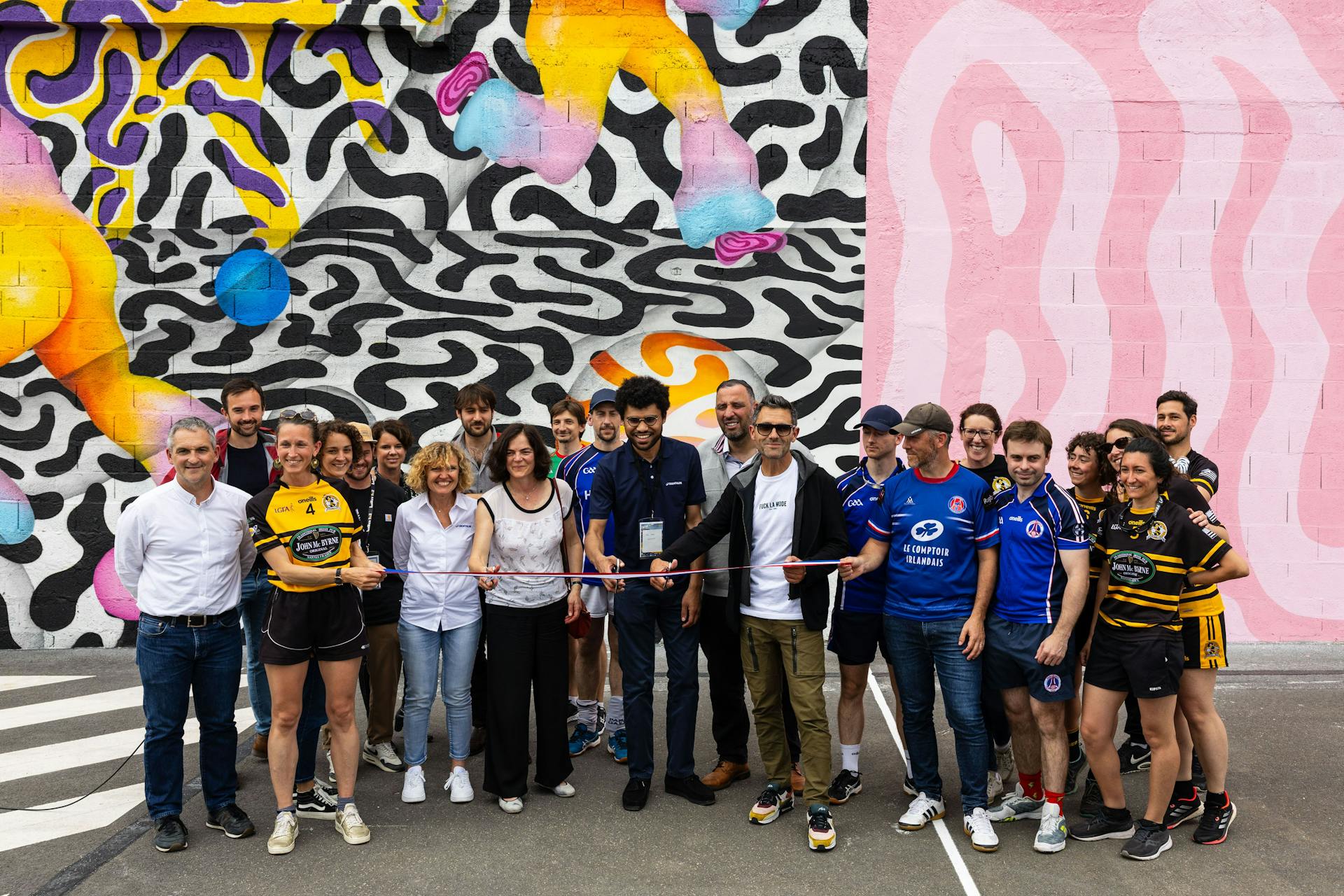 Les membres de la Samoa, du club Don Bosco et de Nantes Métropoe, inaugurent un nouveau terrain de handball gaélique habillé d'une énorme fresque street art en découpant une banderole aux couleurs du drapeau français.