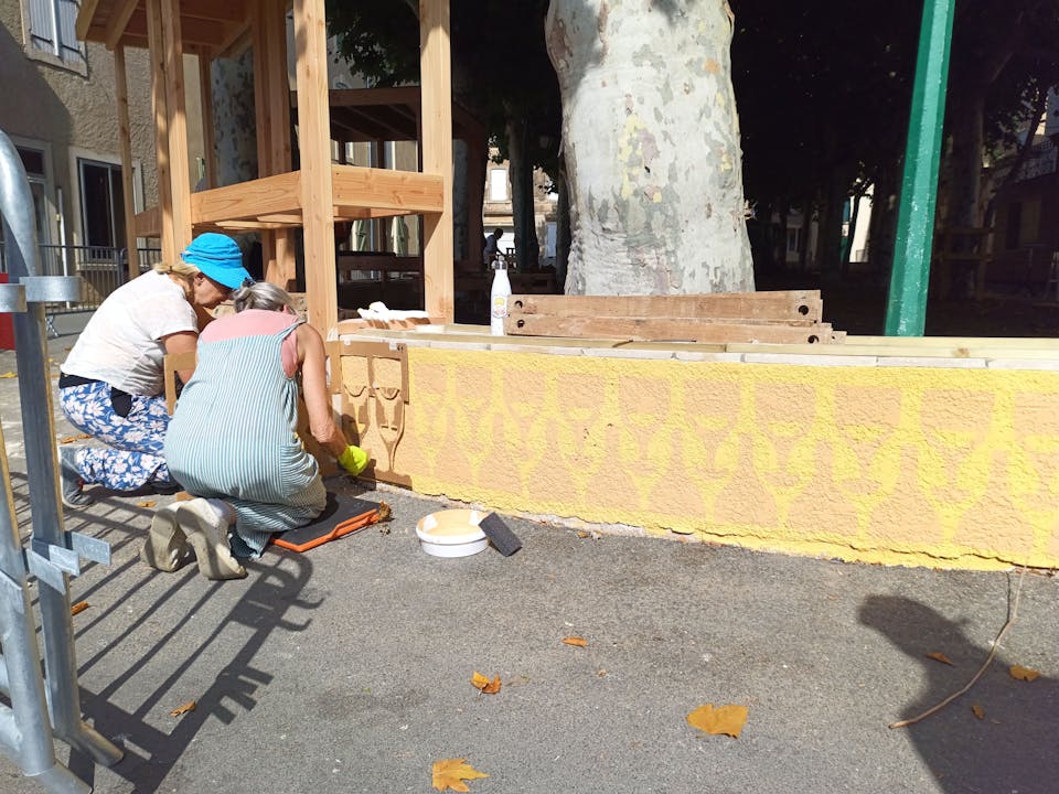 Les habitants bénévoles d'Argeliers travaillent à la construction d'une terrasse extérieure en bois réalisée sur la promenade Marcelin Albert de leur village en compagnie de l'agence de Design Studio Katra.