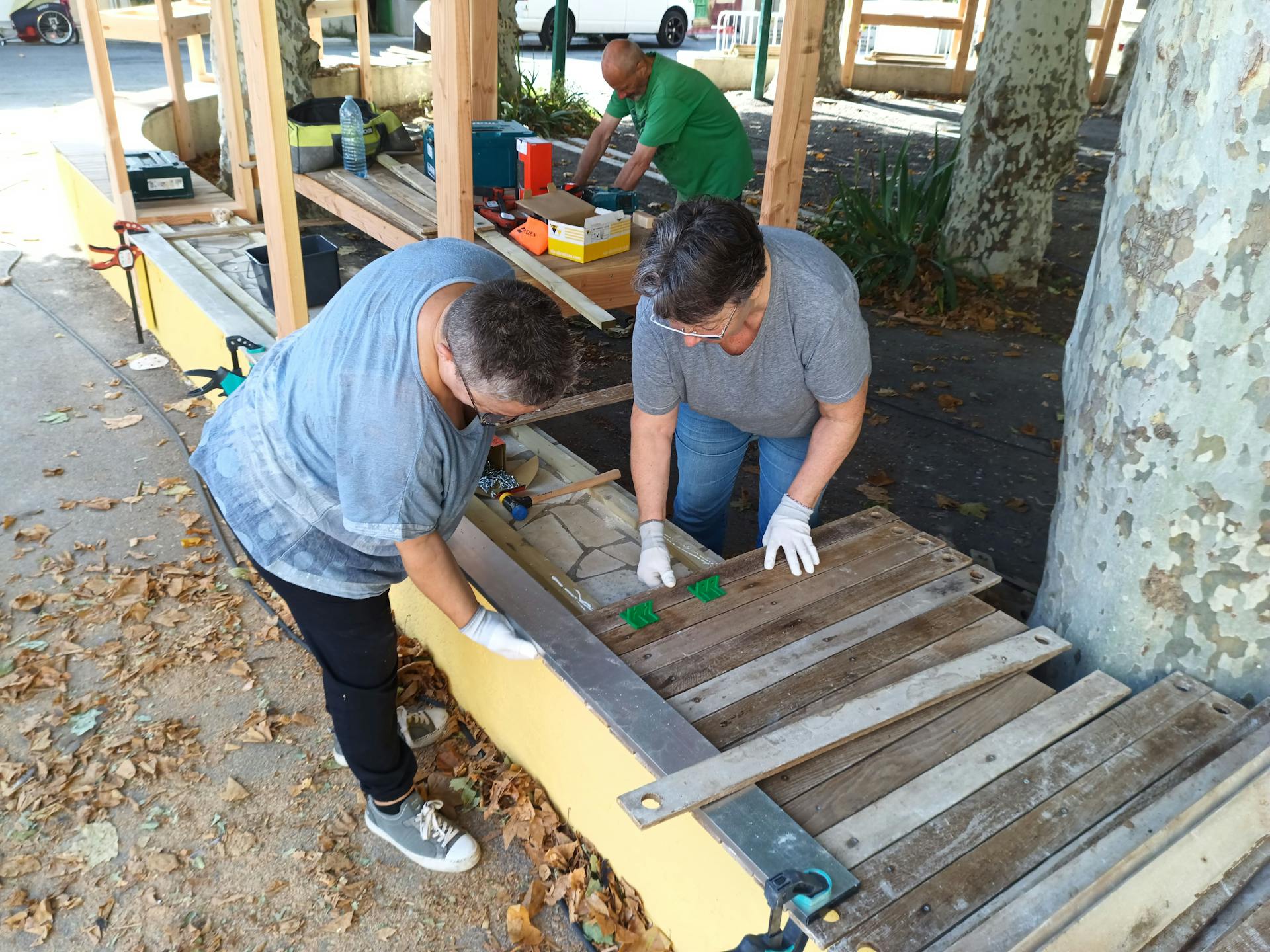 Les habitants bénévoles d'Argeliers travaillent à la construction d'une terrasse extérieure en bois réalisée sur la promenade Marcelin Albert de leur village en compagnie de l'agence de Design Studio Katra.