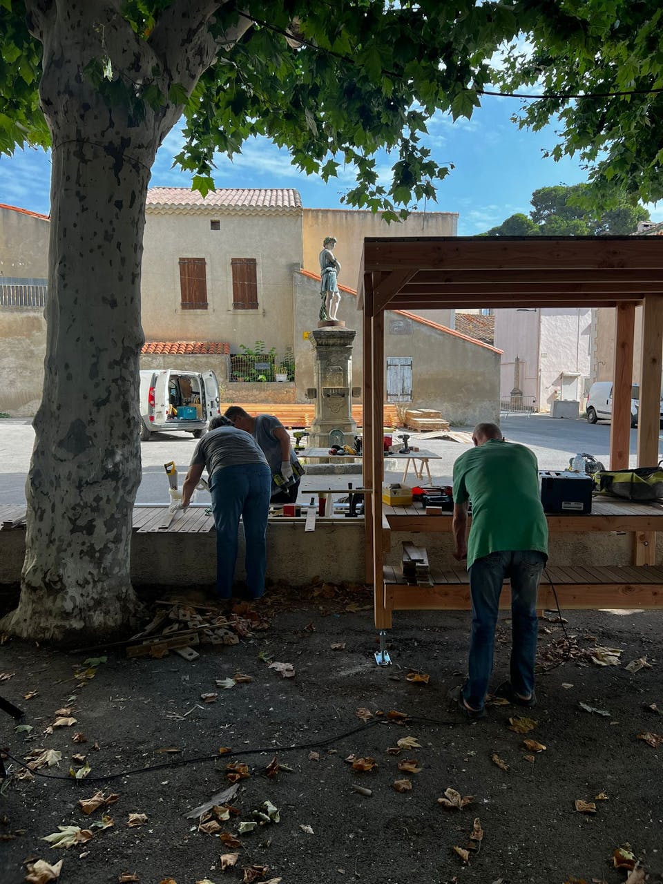 Les habitants bénévoles d'Argeliers travaillent à la construction d'une terrasse extérieure en bois réalisée sur la promenade Marcelin Albert de leur village en compagnie de l'agence de Design Studio Katra.
