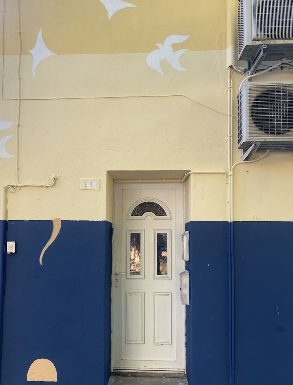 La porte d'un salon de coiffure peint aux couleurs de la promenade Marcelin Albert du village d'Argeliers par l'agence de design Studio Katra.