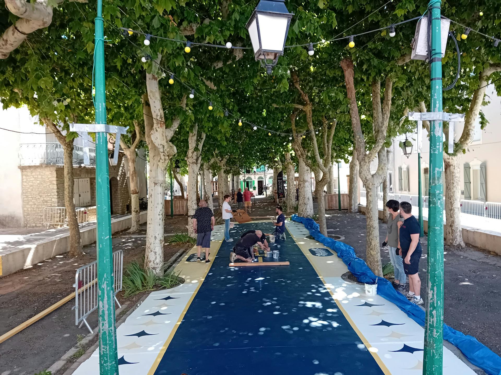 Les habitants bénévoles d'Argeliers travaillent à la réalisation d'une fresque au sol réalisée sur la promenade Marcelin Albert de leur village en compagnie de l'agence de Design Studio Katra.