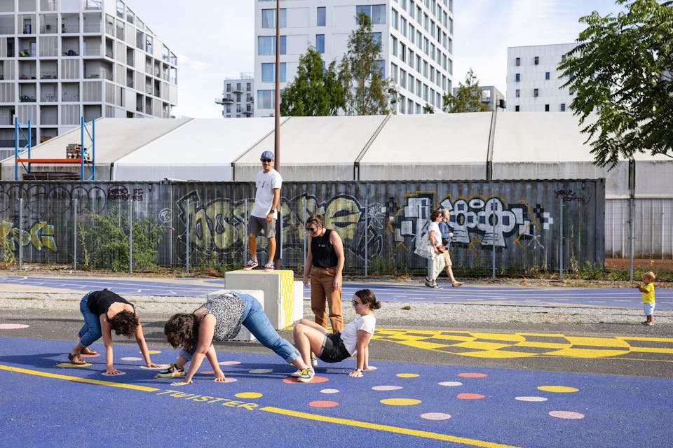 Des passants se prêtent au jeu du "Twister" à l'aide d'un plateau de jeu peint au sol sur l'Île de Nantes.