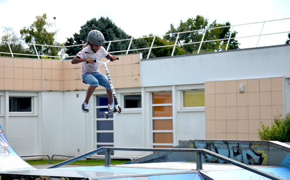 Urban culture 2016 : un jeune garçon décolle sur une rampe de skatepark avec sa trottinette.