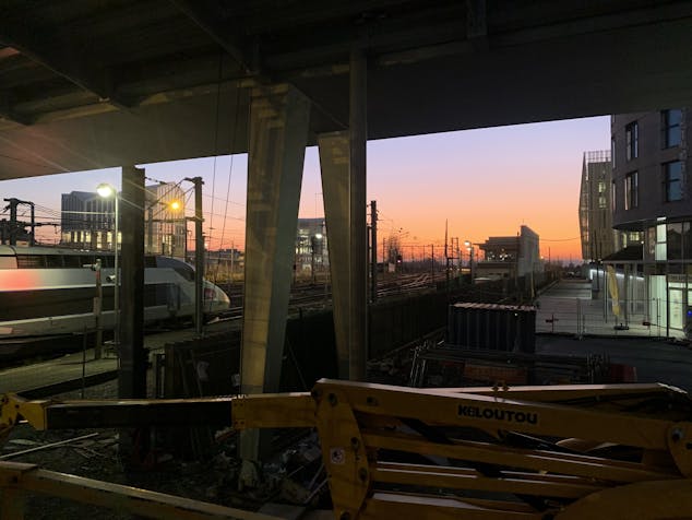 Photo d'un coucher de soleil sur les rails d'une gare.