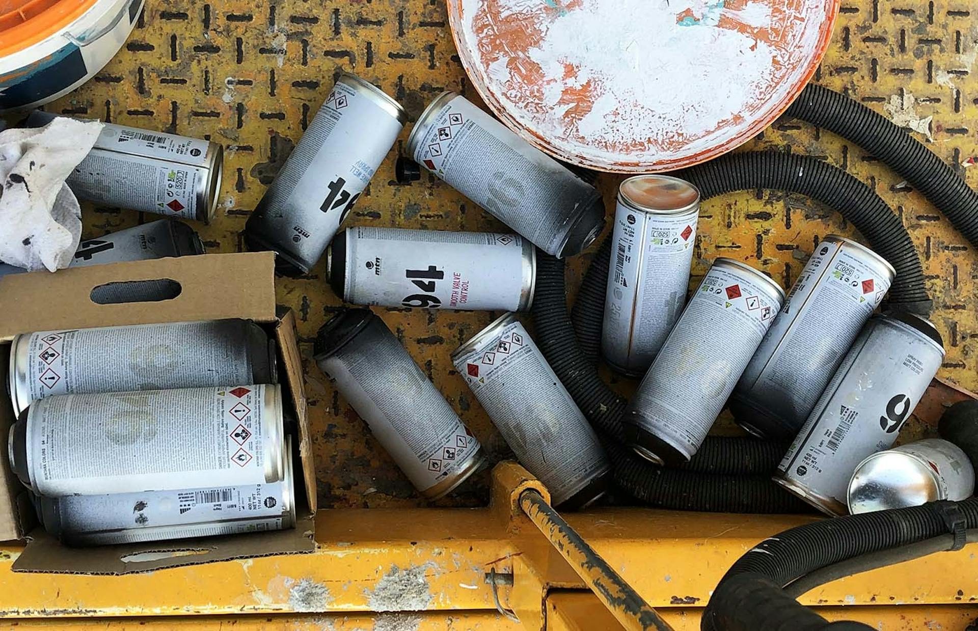 Des bombes de peintures vides entreposées sur une nacelle télescopique lors d'un chantier fresque.