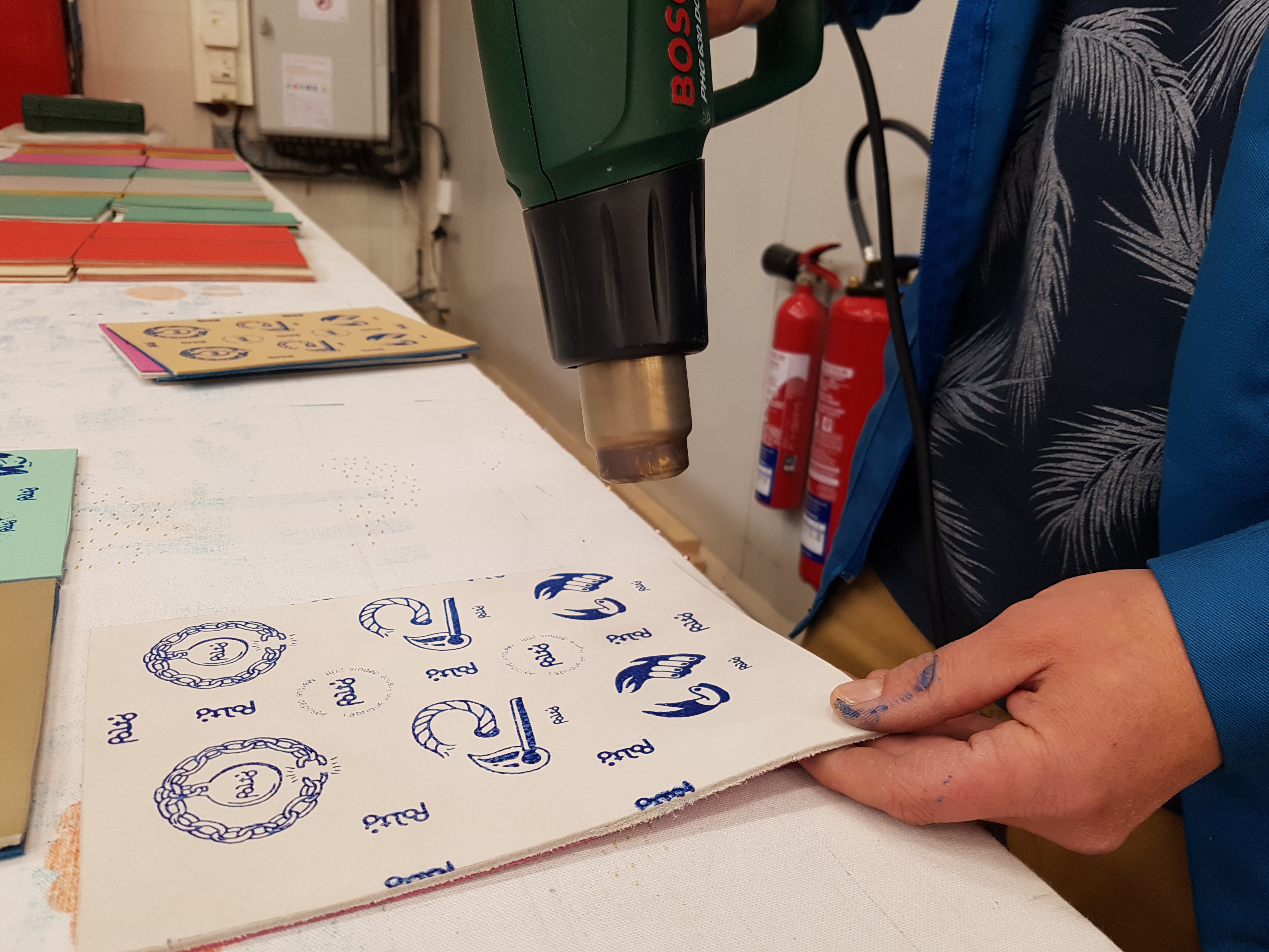 Utilisation d'un décapeur thermique pour appliquer des illustrations du Studio Katra sur des palets en cuirs.