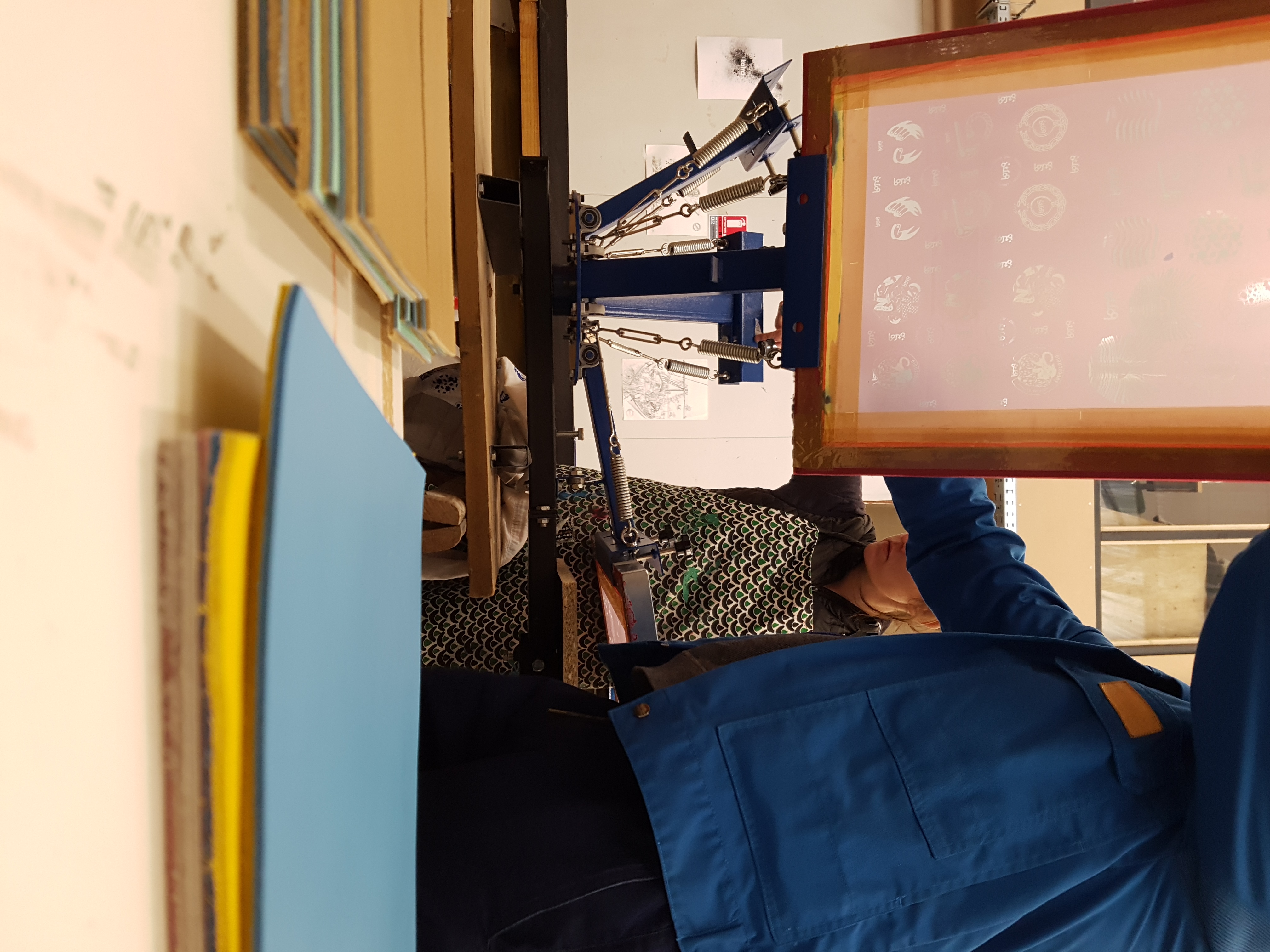 Une presse de sérigraphie manipulée par deux personnes lors de la création de palets en cuir d'intérieur. 