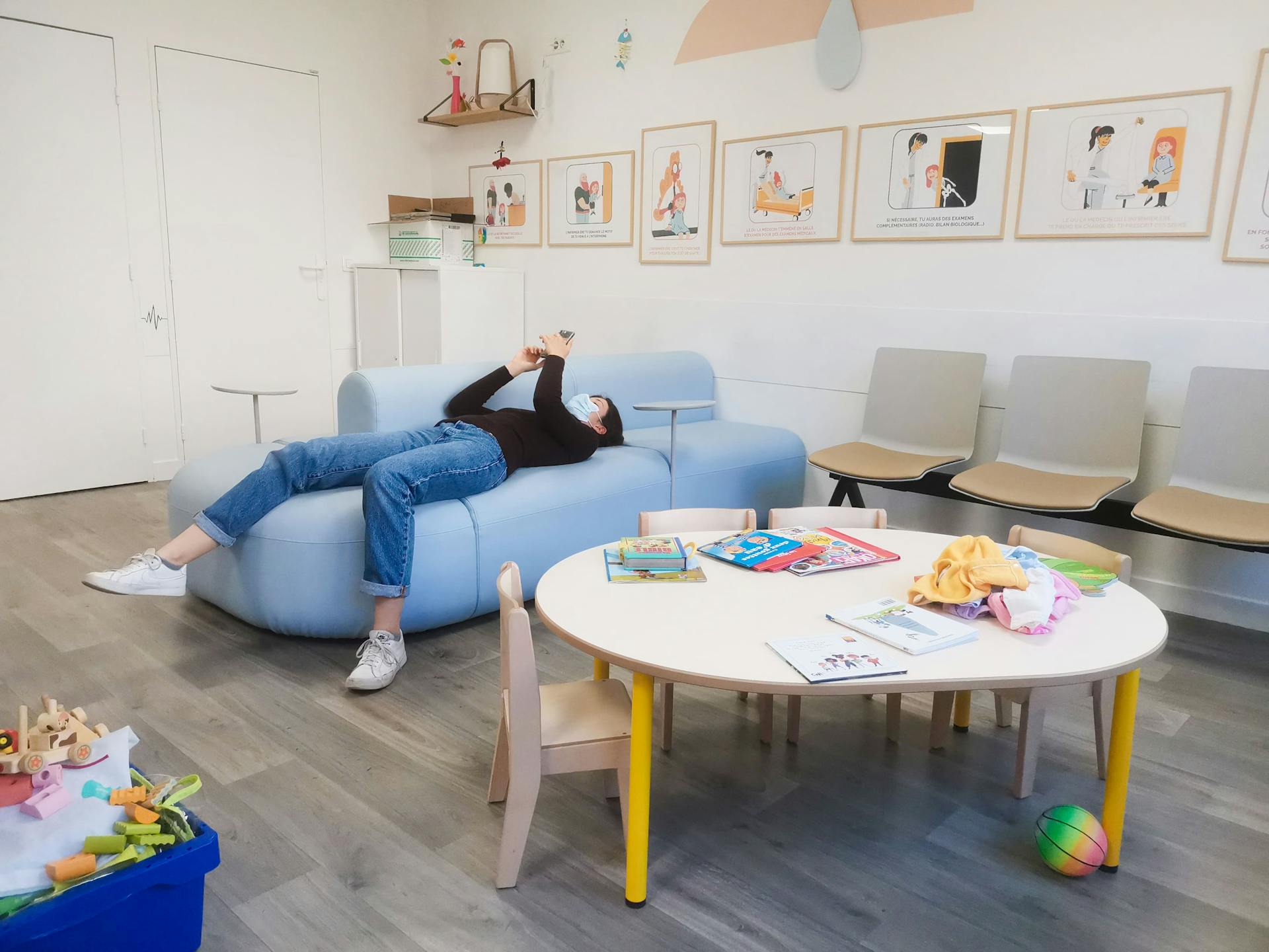 Une personne portant le masque, allongée sur un sofa dans une salle d'attente CHU de Montpellier.