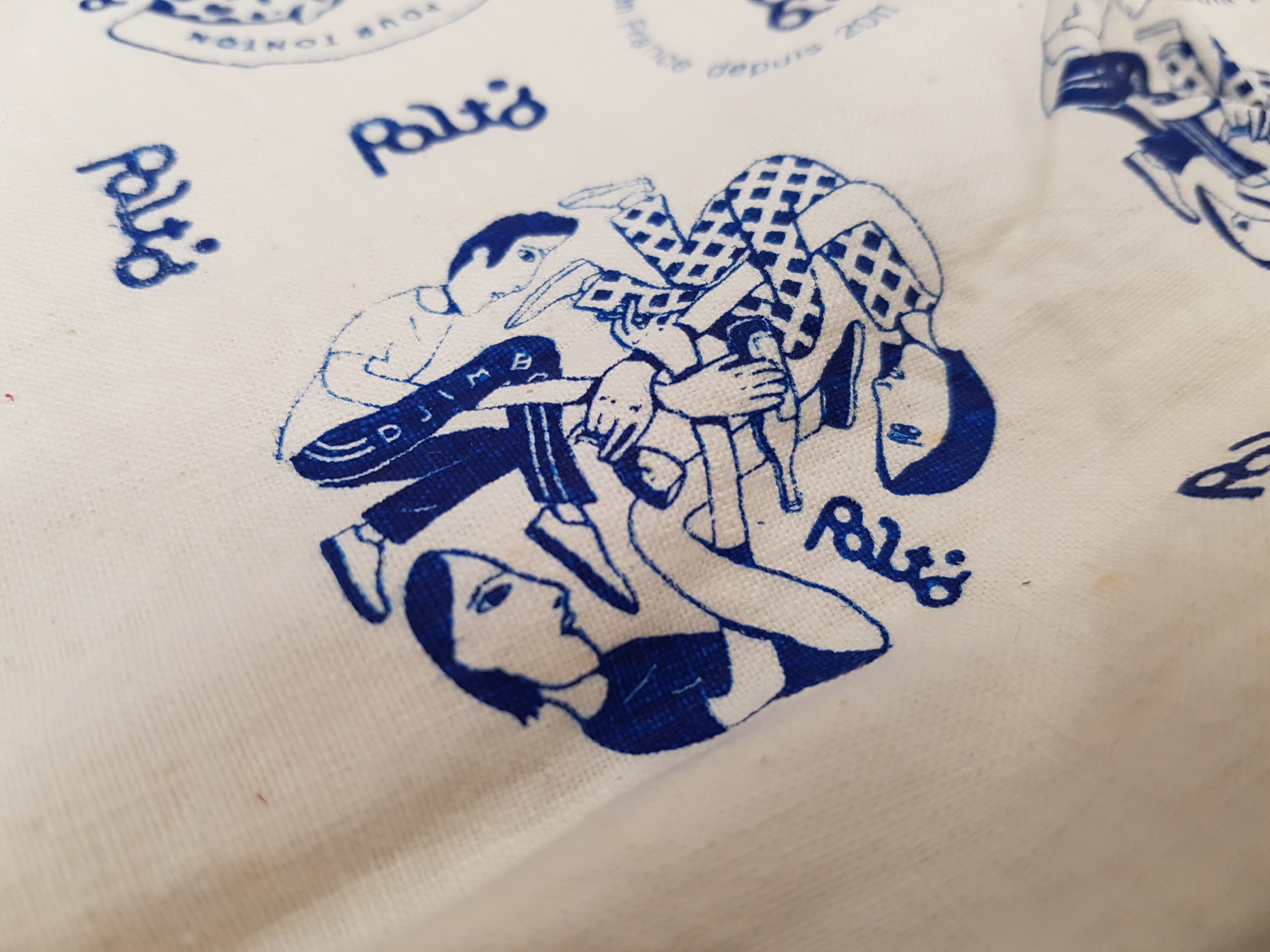 Illustration de 3 personnages se tenant les poignets et formant un triskell breton, imprimée en sérigraphie sur du tissu dans les ateliers du Studio katra. 