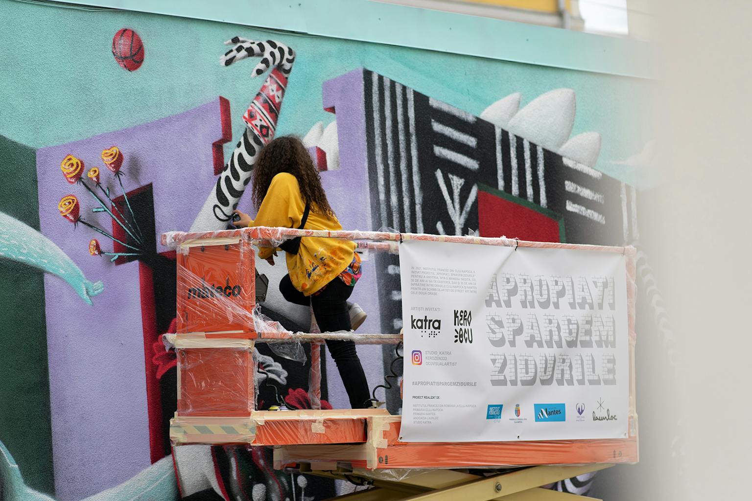 Ocü, la partenaire de Kero Zen, peignant la peinture murale depuis une nacelle télescopique.