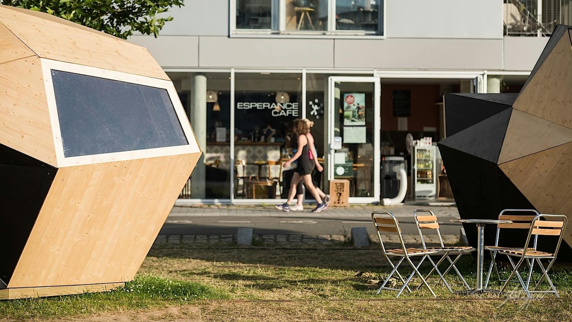 Deux coureuses passant au loin entre deux modules en bois.