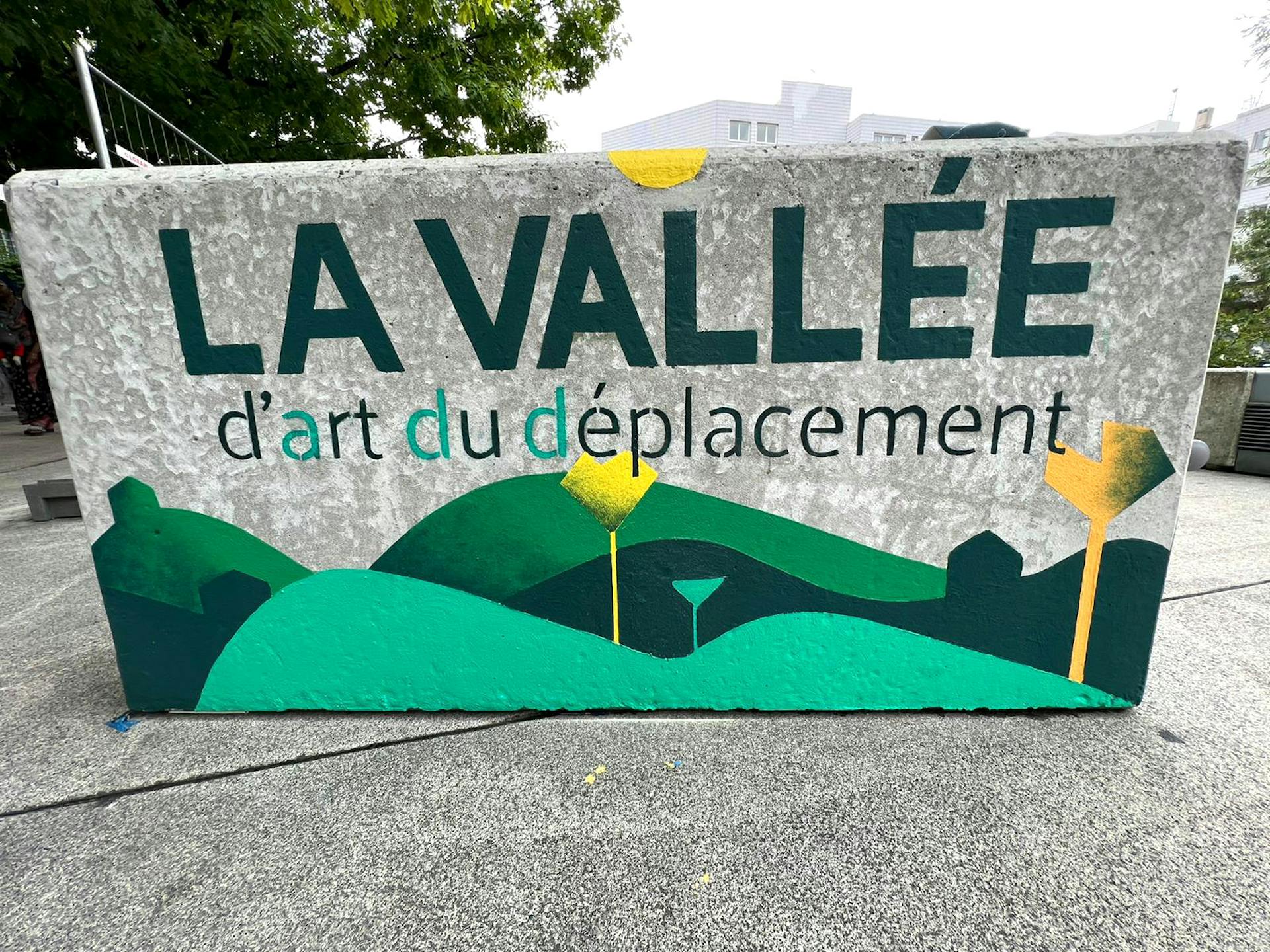 Un bloc de béton accueillant une peinture en lettres "l'Art du Déplacement", marquant le début d'un parcours d'obstacle.