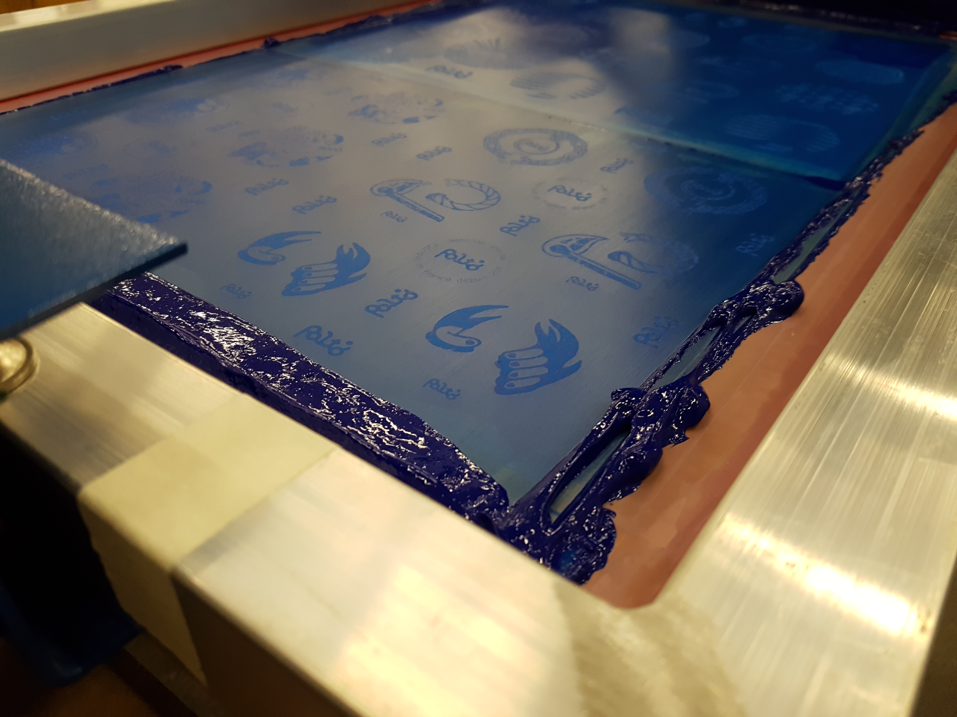 Focus sur le cadre d'une presse de sérigraphie lors de l''impression d'illustrations du Studio Katra sur du cuir.