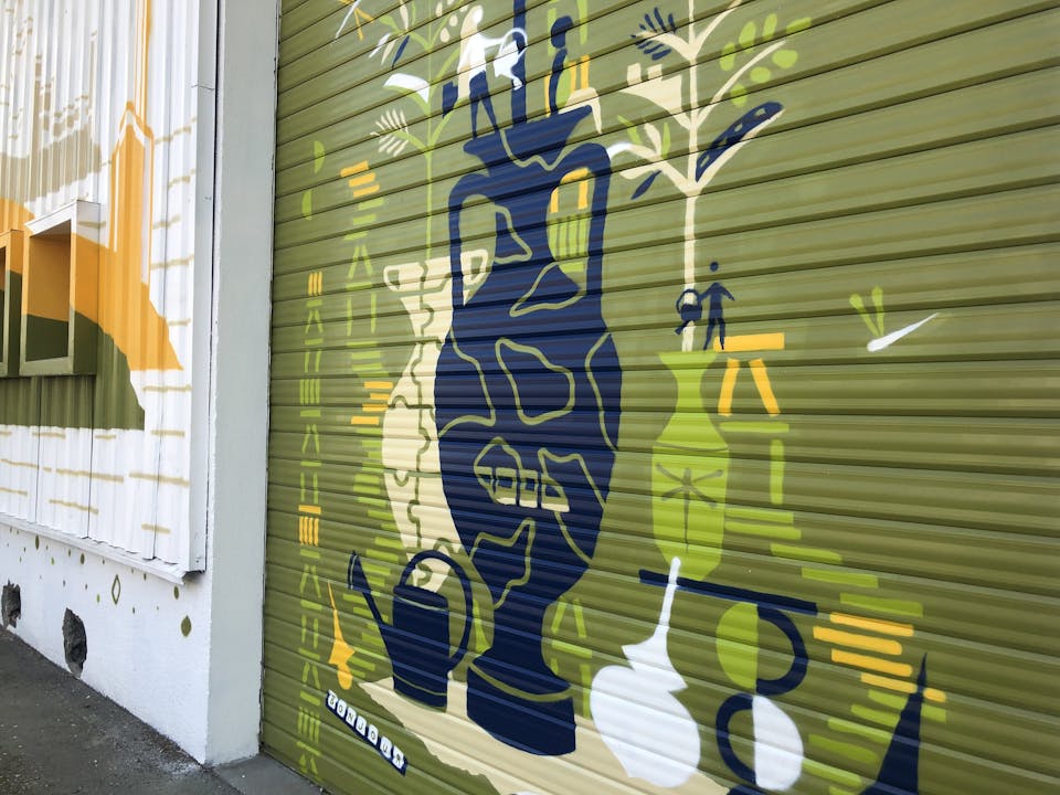 Une grande porte de garage repeinte à l'aide d'une fresque murale street art par l'agence de design graphique Studio Katra.