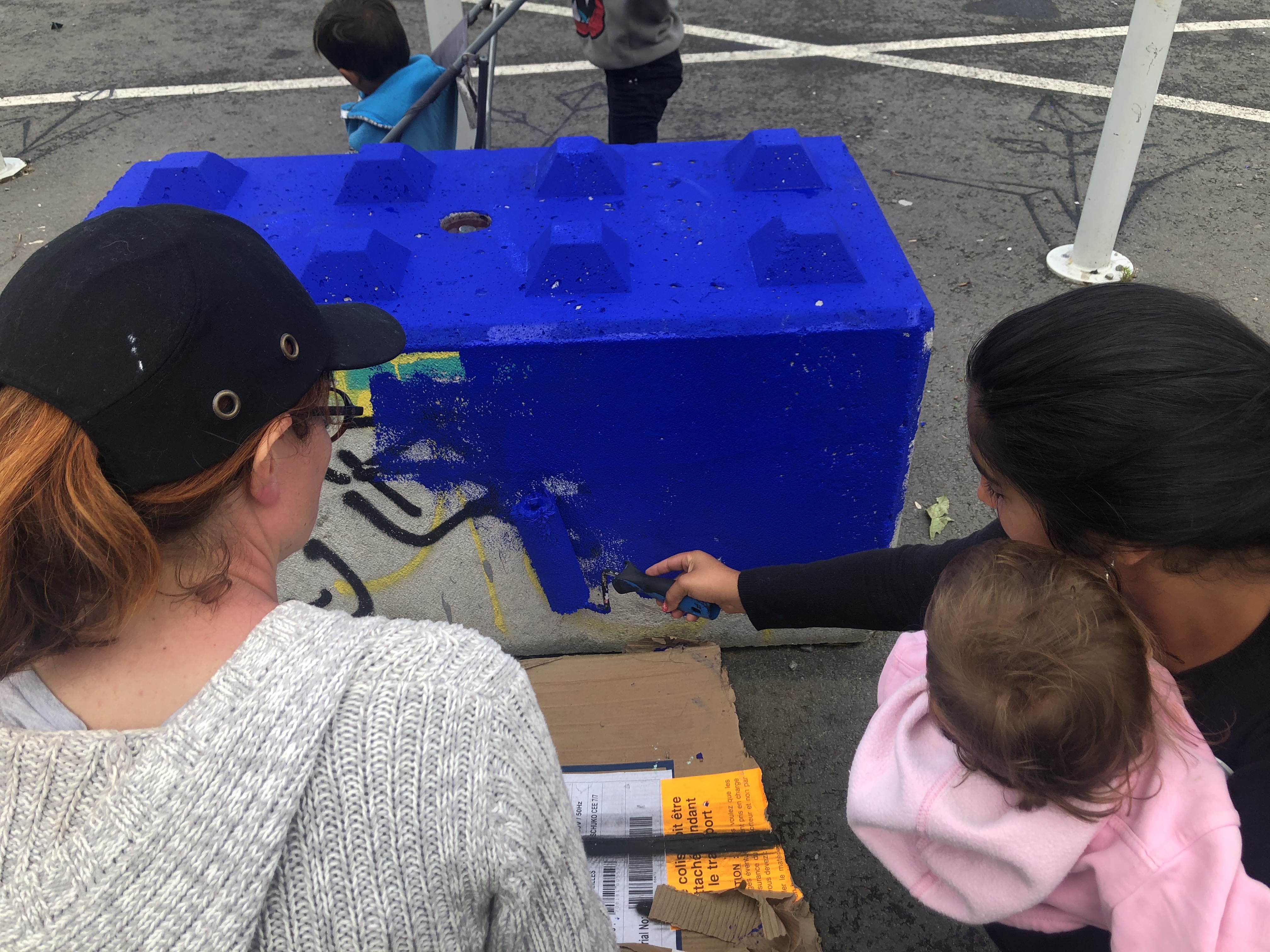Famille peignant un bloc de béton à l'entrée de la zone libre d'art de Transfert.