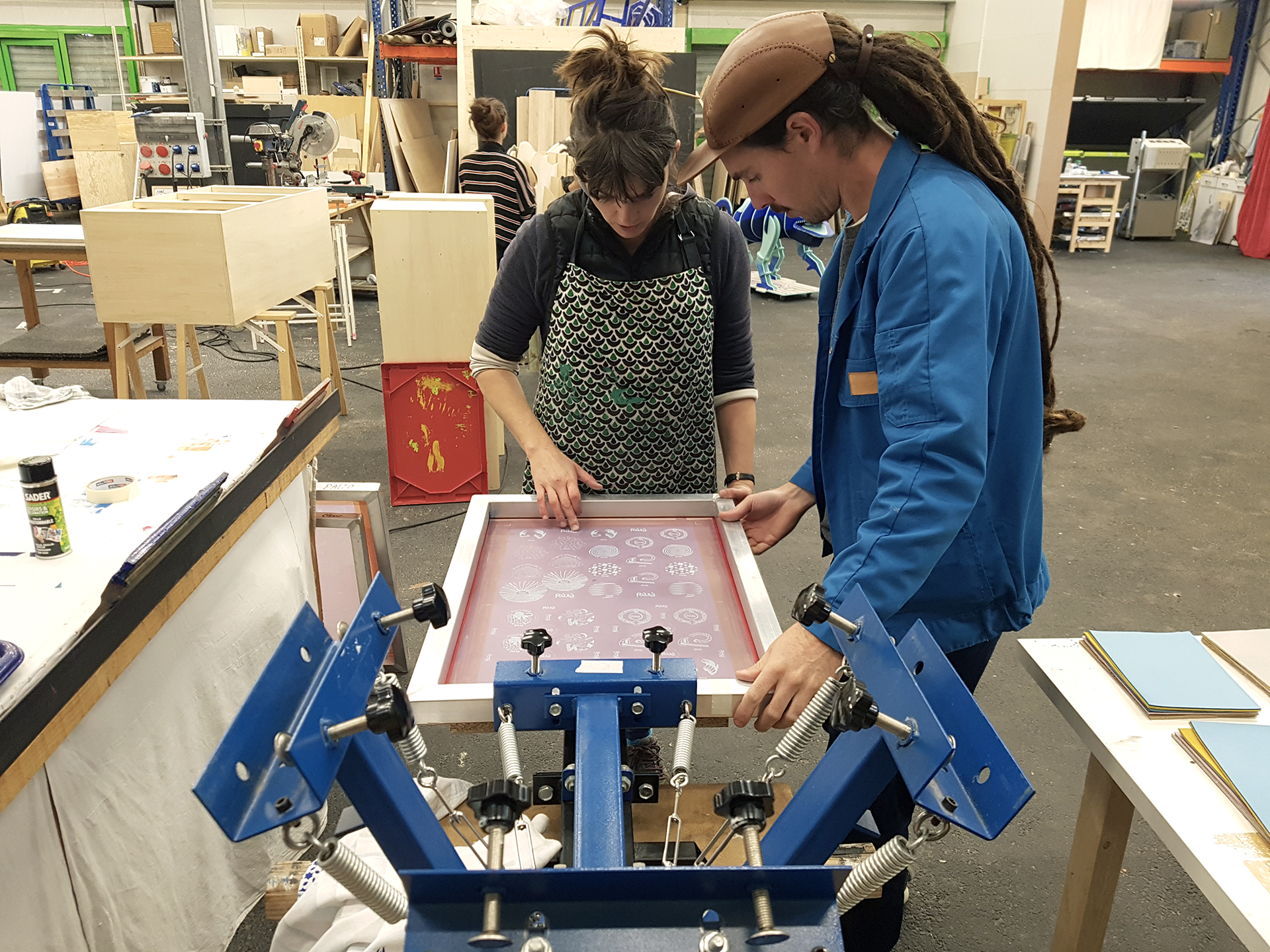 Un homme et une femme utilisent une presse de sérigraphie pour imprimer des illustrations sur du cuir.
