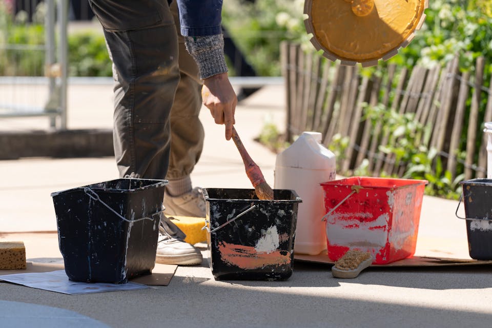 Une personne essuyant son pinceau dans un pot de peinture.