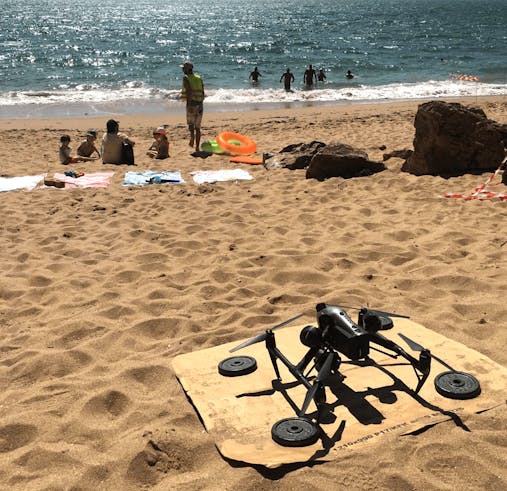 Photo d'un drone à l'arrêt, posé sur le sable.