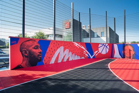 Angle d'un terrain de basket Caisse d'épargne décoré par une fresque murale arborant les visages de Boris Diaw et Marielle Amant.