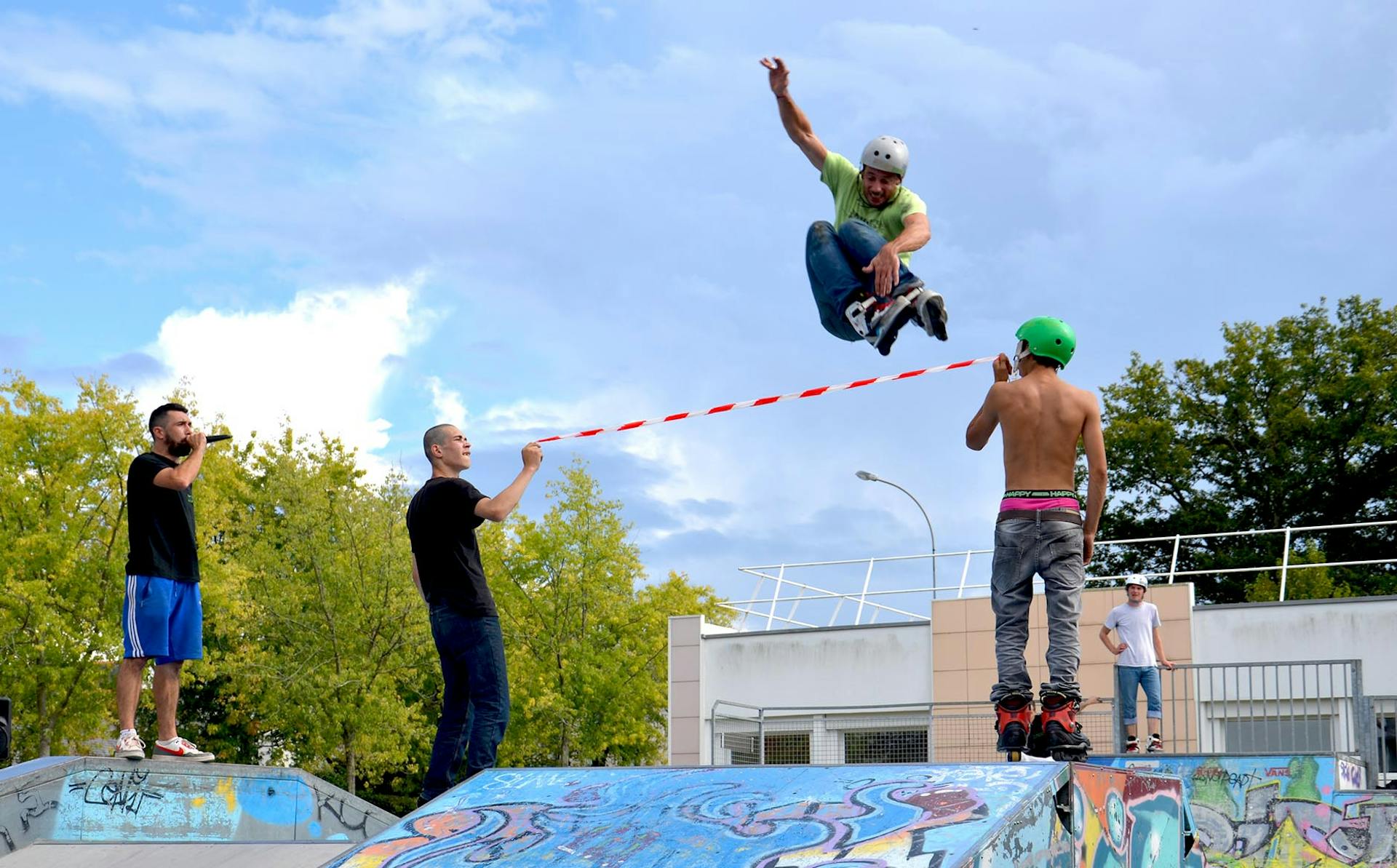 Festival Urban culture 2016 de la Chapelle-sur-Erdre : un homme en rollers s'élance au-dessus d'une corde tenue par deux autres personnes.