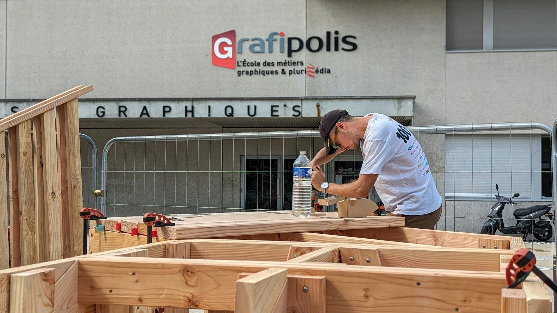 Assemblage d'un promontoire en bois réalisé par l'agence de design Studio Katra, installé devant l'école la Joliverie dans le cadre du projet "le Champ des Signes".