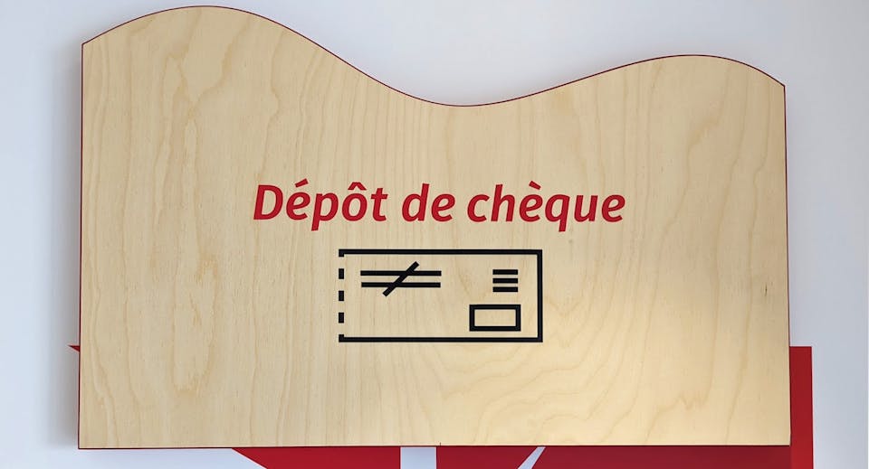 Une entête en bois pour distributeur bancaire, signalant un lieu de dépôt de chèques.