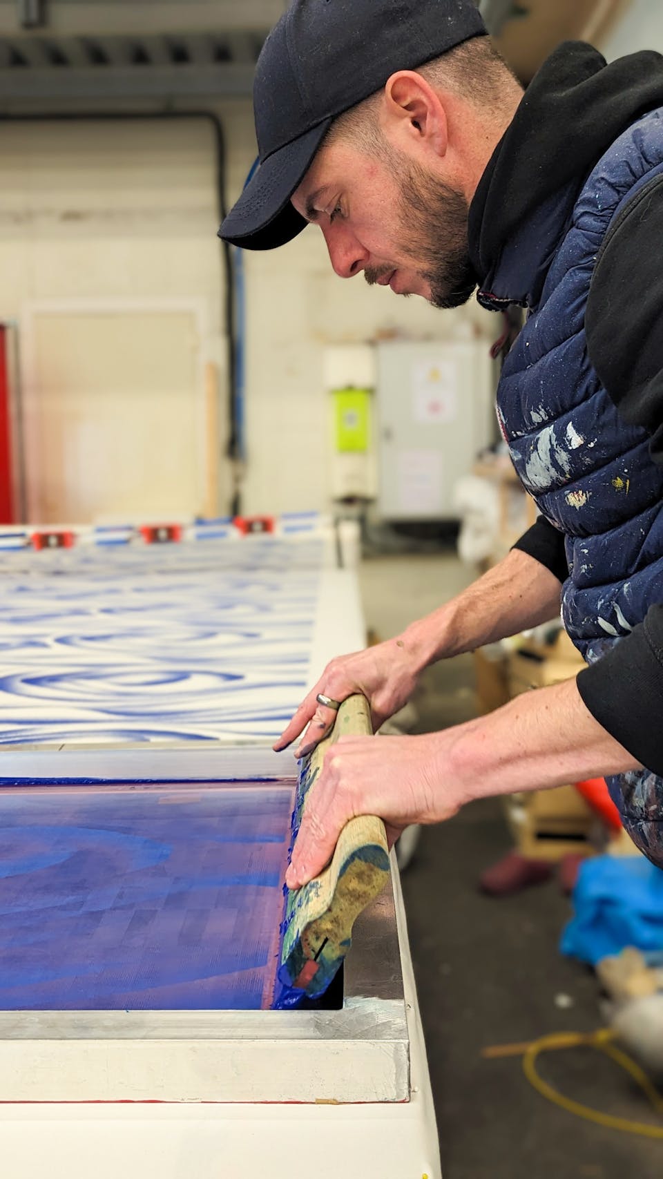 Camille Pansard, ennoblisseur textile, poussant une raclette sur un cadre de sérigraphie pour une impression textile.