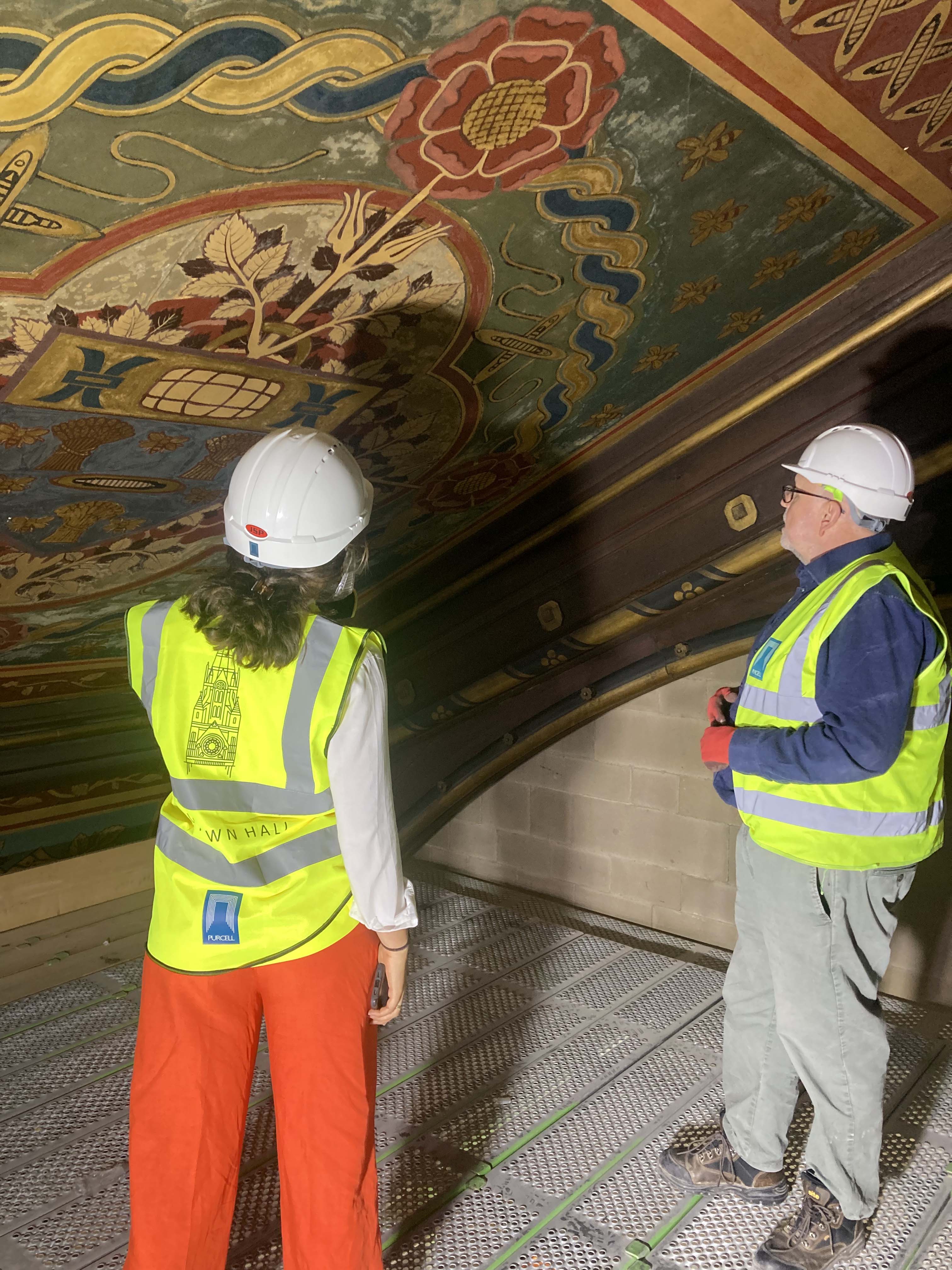 Heritage specialists and construction workers looking at a painting on a panel 