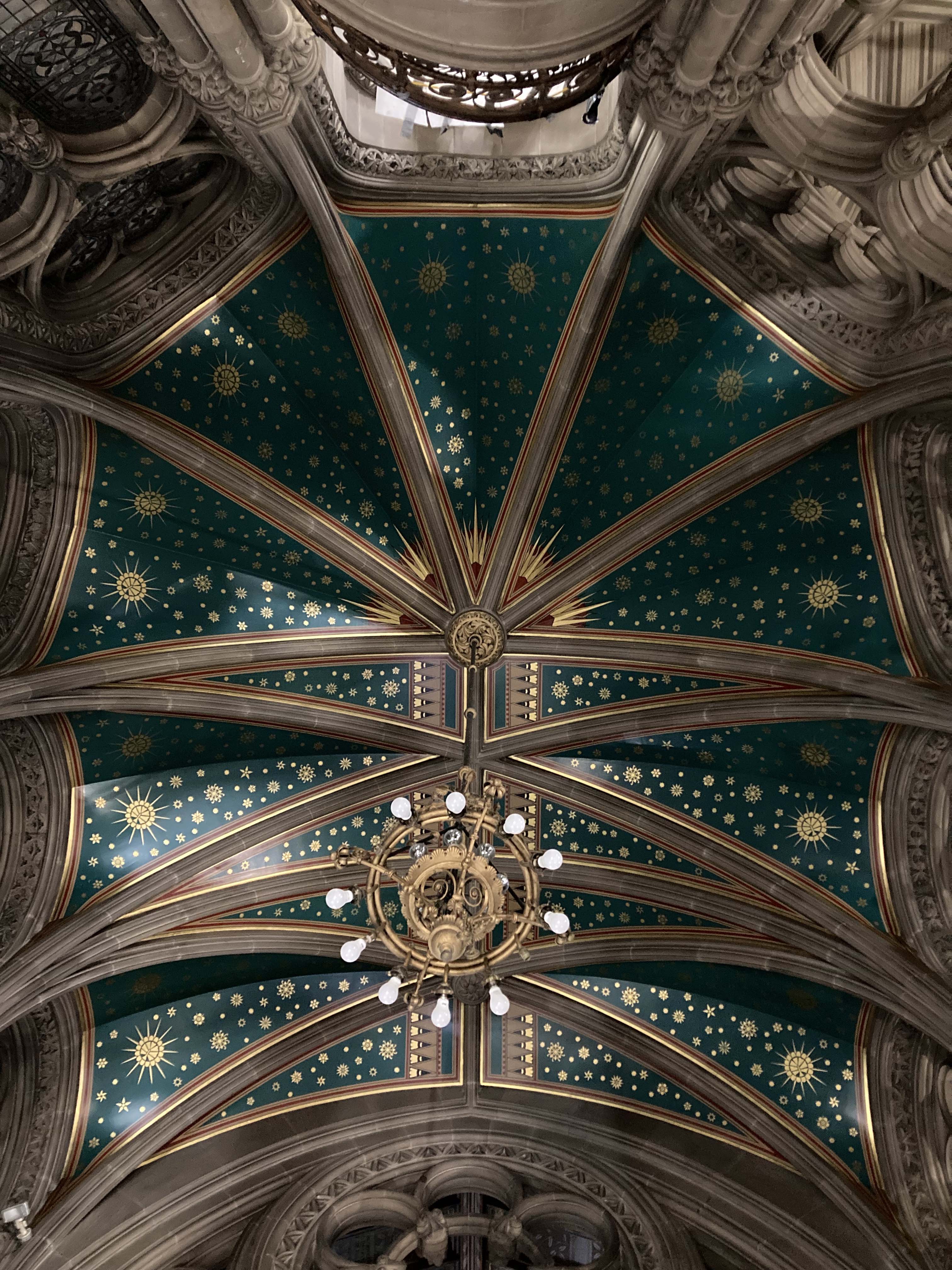 The ceiling of Manchester Town Hall, with detailed paintings and wooden beams.