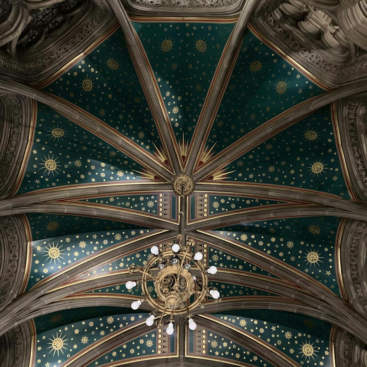The ceiling of Manchester Town Hall, with detailed paintings and wooden beams.