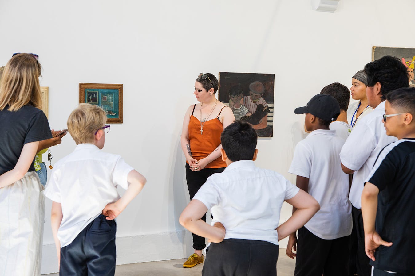 a group of school children gather round a painting in a gallery, as part of a guided tour