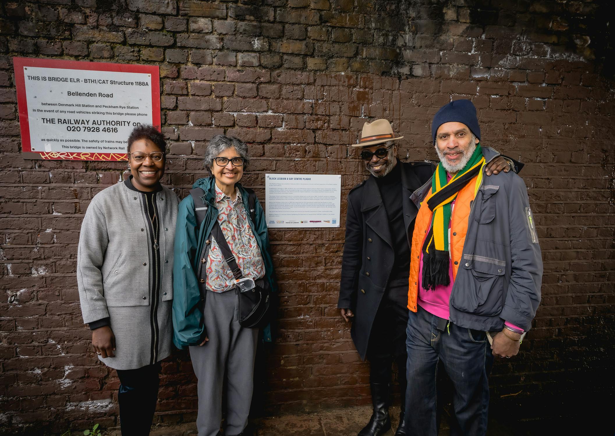 Former staff members of the Black Lesbian and Gay Centre standing in front of a wall mounted Plaque in the background