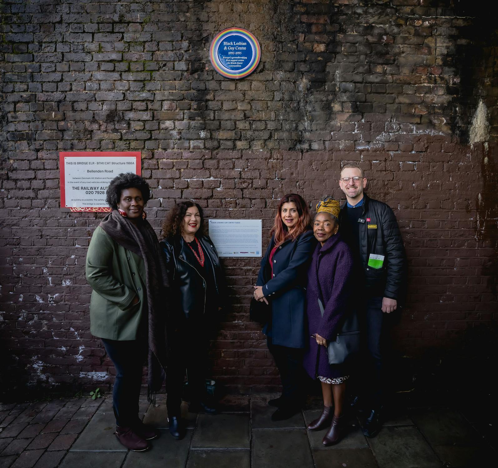 Former staff members of the Black Lesbian and Gay Centre standing in front of a wall mounted Plaque in the background