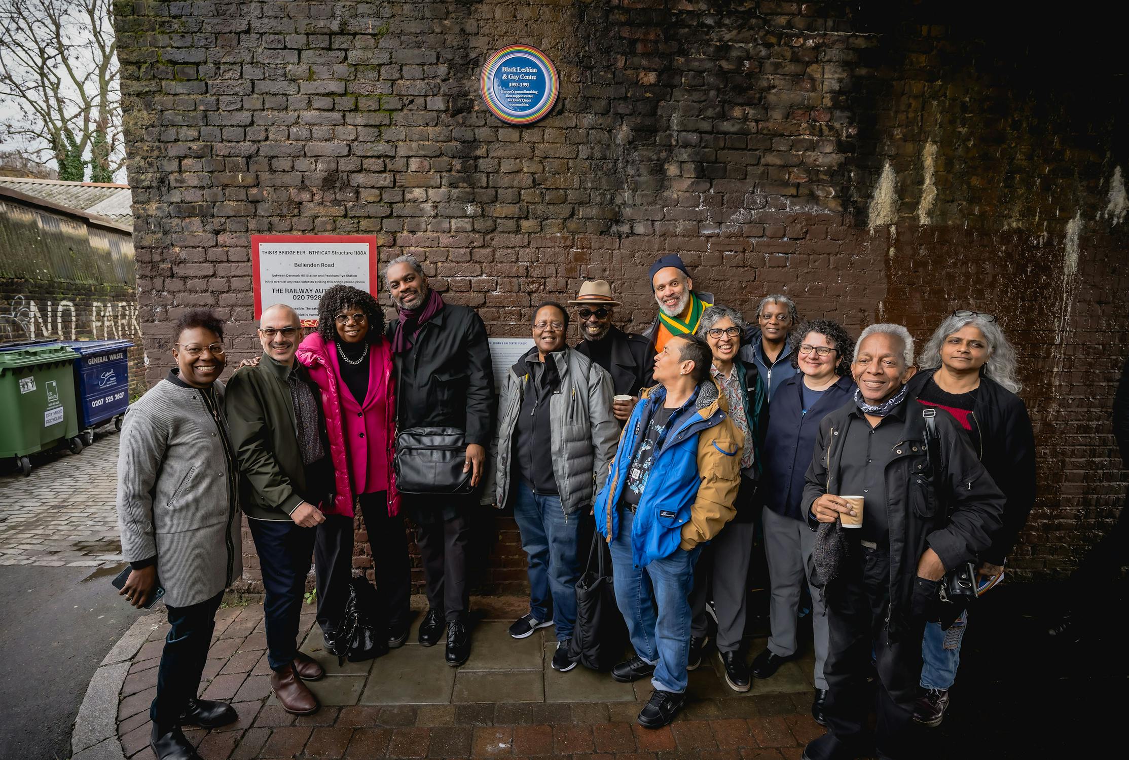 Former staff members of the Black Lesbian and Gay Centre standing in front of a wall mounted Plaque in the background