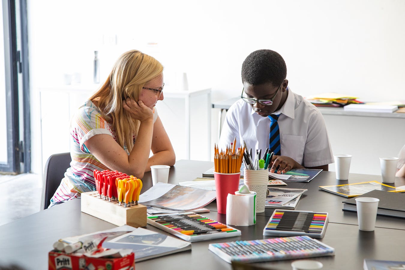 a white woman and a black school child taking part in a creative workshop