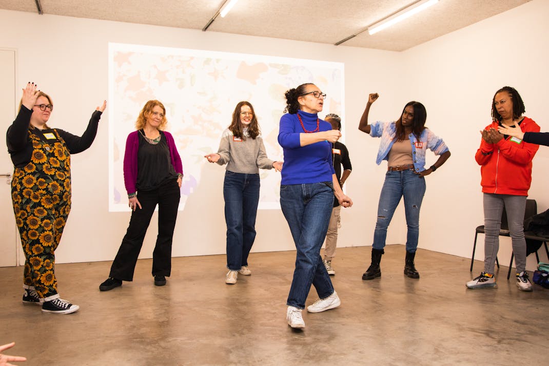 a group of women dance and clap in front of a digital projection